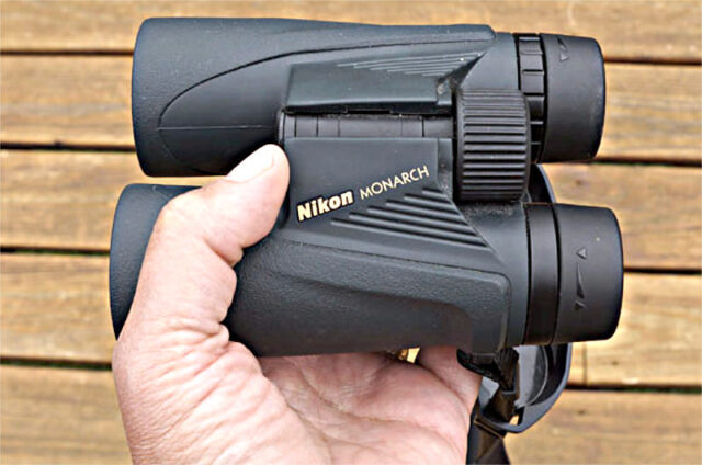 Holding a pair of Nikon Monarch binoculars.