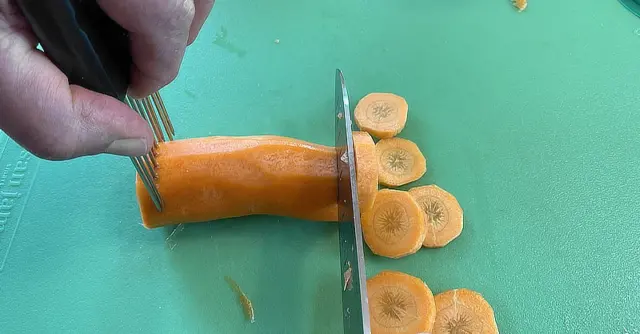 slicing carrots while holding with vegetable pronged holder