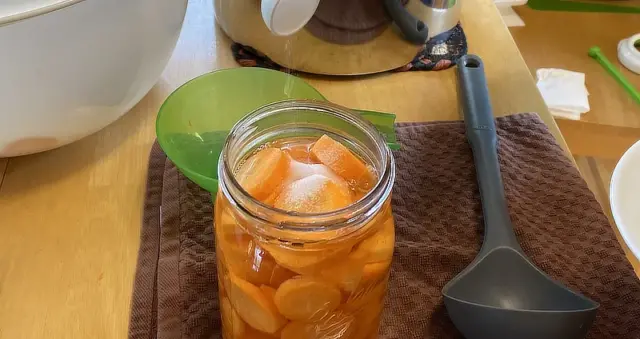 adding salt to canning jar of carrots